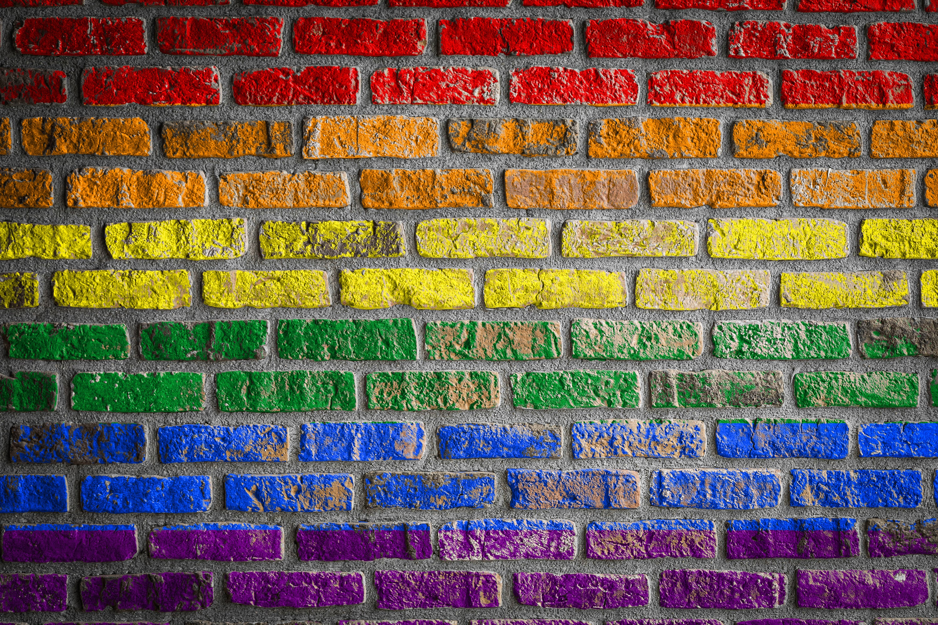 brick wall painted with horizontal rainbow stripes