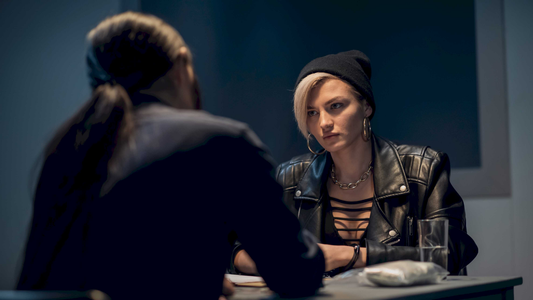 A detective interviewing a suspect across a table, representing the real-life challenge of building a case without relying on a confession
