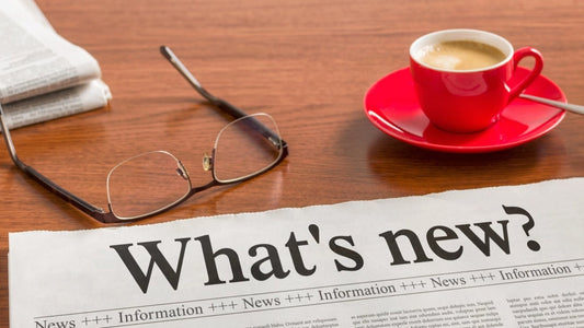 newspaper at bottom saying What's new with a red coffee cup and glasse on the desk above