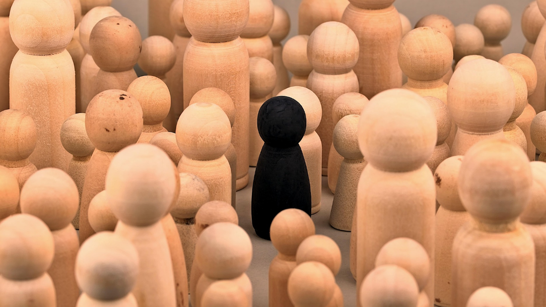 A lone black figure stands apart from a crowd of identical figures, symbolizing the introverted writer navigating the social world of networking
