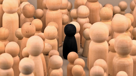 A lone black figure stands apart from a crowd of identical figures, symbolizing the introverted writer navigating the social world of networking