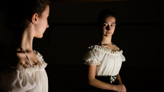 A woman gazes at her reflection in a mirror, symbolizing the introspective practice of writing honestly for yourself rather than for outside approval