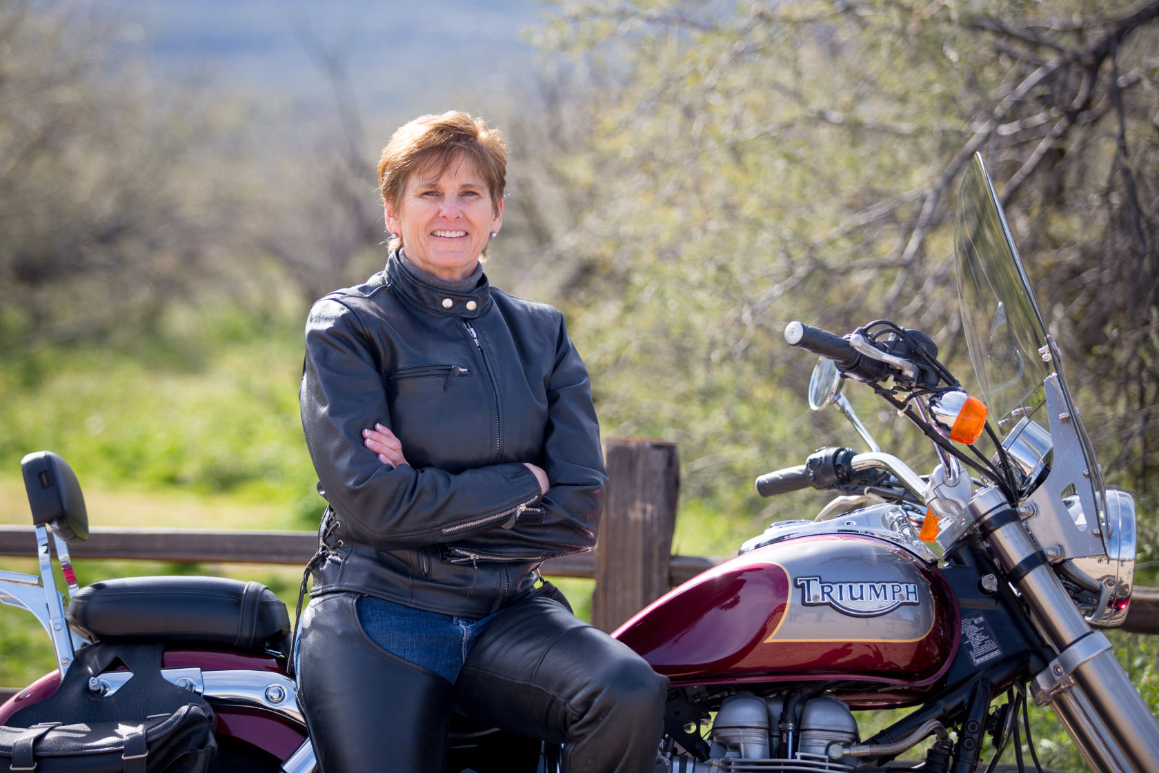 Sapphic fiction author Alison Naomi Holt in a leather jacket leaning against a motorcycle